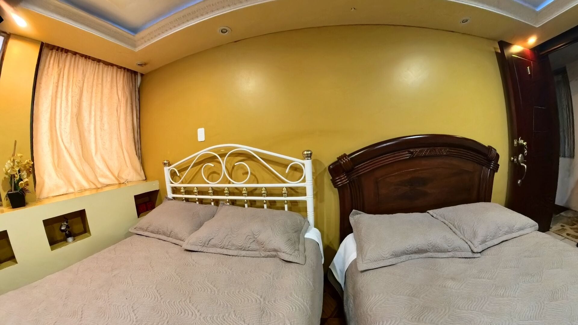 Una habitación con dos camas, una ventana con cortinas y una puerta.