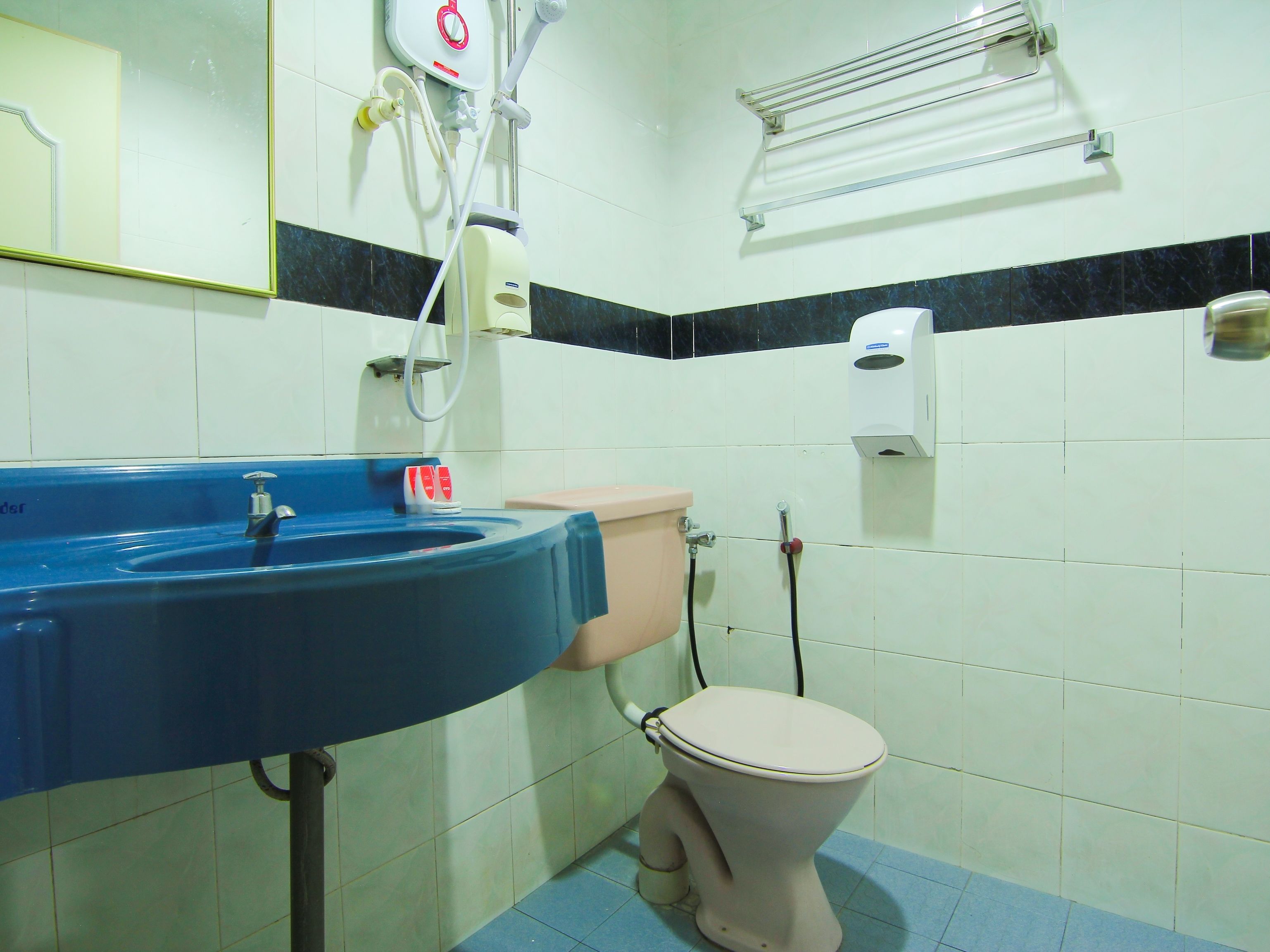 A bathroom with a blue sink, a toilet, and a hand dryer.