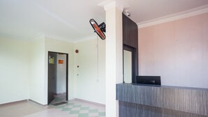 Een receptiegedeelte met een receptiebalie, een beveiligingscamera en een deur naar een lift.