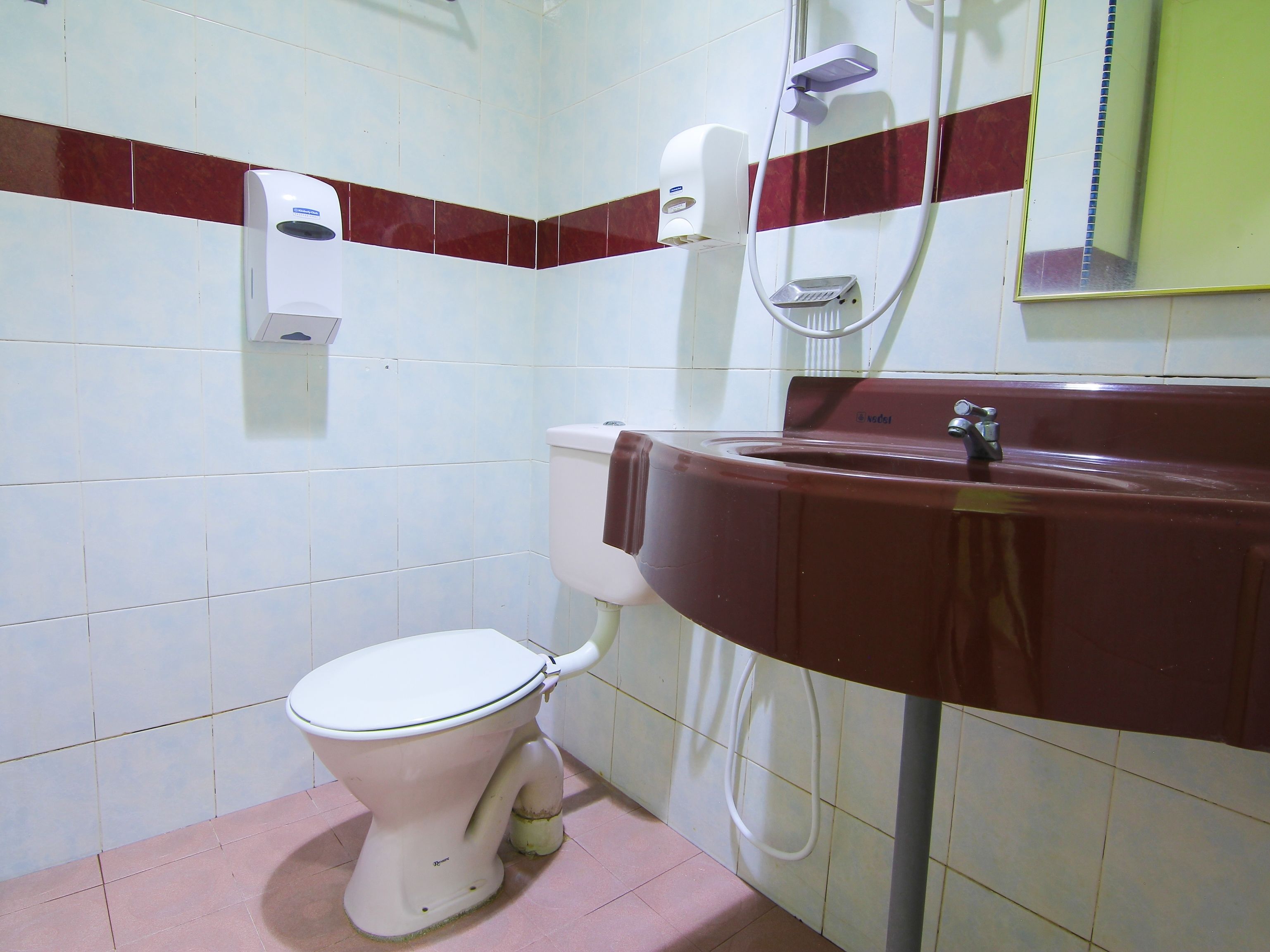 Un baño con un inodoro blanco, un lavabo marrón y un secador de manos.