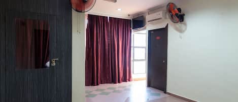 Un pasillo de hotel con piso a cuadros, un felpudo, una puerta con un número y dos ventiladores.