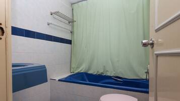 Een badkamer met bad, toilet en douchegordijn.