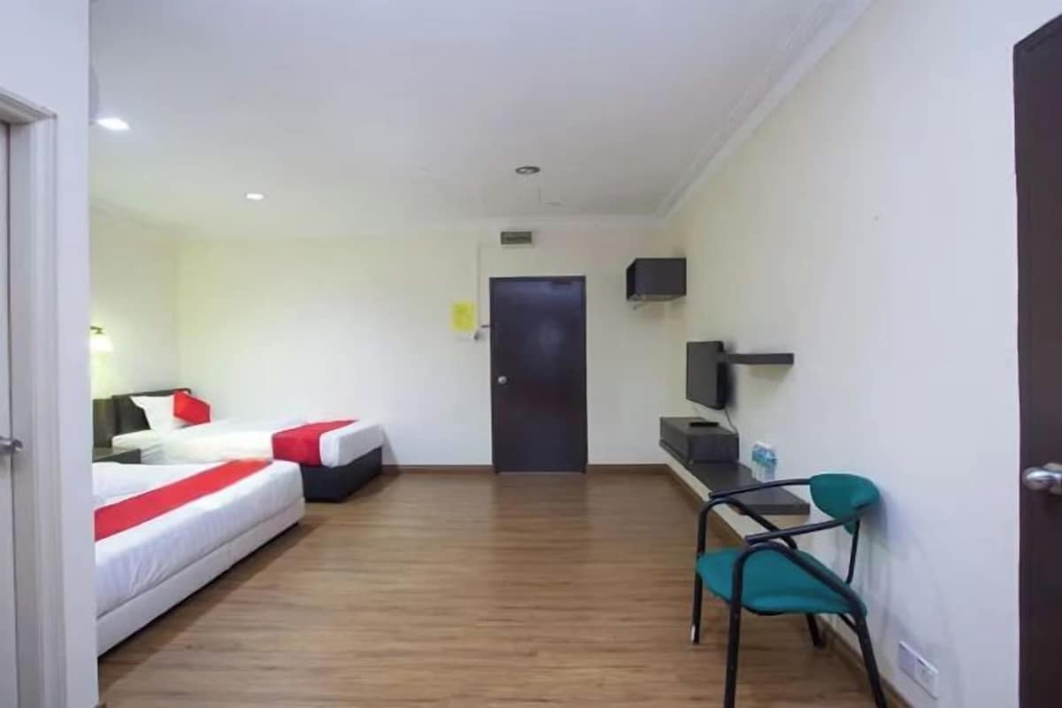 Quarto de hotel com duas camas, uma escrivaninha, uma cadeira e uma televisão.