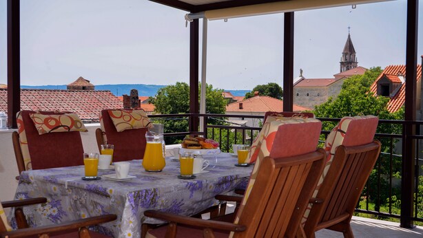 Ein Balkon mit Frühstückstisch, mit Blick auf eine Stadt mit traditionellen Gebäuden und einem Kirchturm.