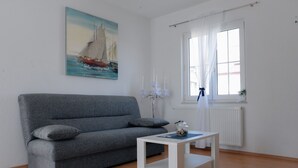Ein Wohnzimmer mit grauem Sofa, einem weißen Couchtisch und einem Segelbootgemälde an der Wand.