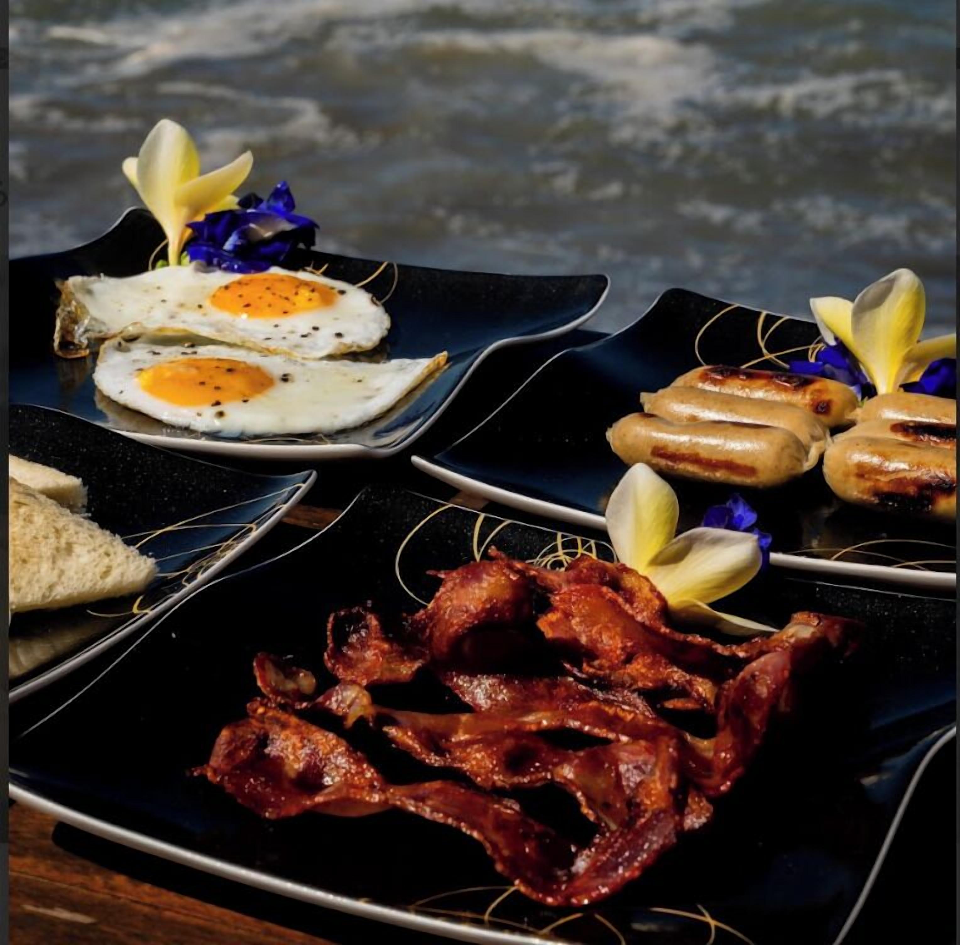 A breakfast plate with fried eggs, sausages, bacon, and toast.