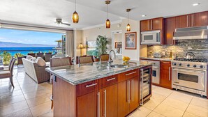 A modern kitchen with a large island, stainless steel appliances, and a view of the ocean. - Maui Resort Rentals: Honua Kai Konea 625 - 6th Floor 3BR w/ Ocean Views from Every Room! (Lahaina)