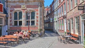Una calle empedrada con mesas al aire libre, edificios de ladrillo e iglesia con tejado rojo.