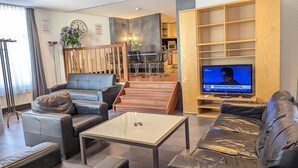 Una sala de estar moderna con sofás de cuero, una mesa de centro de vidrio y un televisor que muestra el Festival de Cine de Venecia.