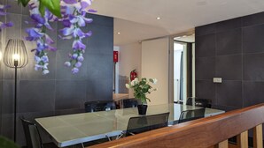 Una sala de reuniones moderna con una mesa de vidrio, paredes oscuras y una barandilla de madera.
