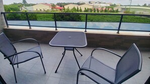 A balcony with two chairs and a small table, overlooking a green landscape and buildings. - Bam House B&B (Tainan)
