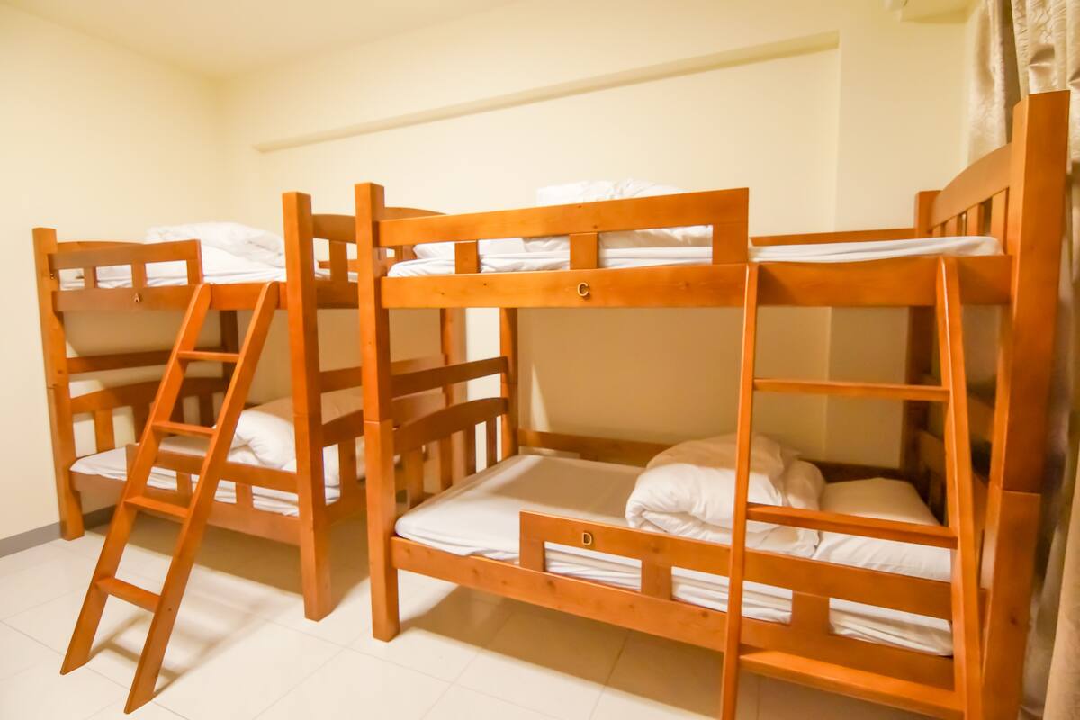 Une chambre avec trois lits superposés, chacun équipé d’une échelle en bois.