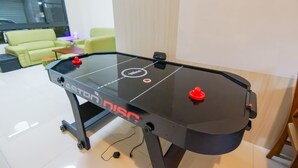 A table hockey table with a black surface and red puck holders, located in a room with a green sofa and a whiteboard in the background. - Bam House B&B (Tainan)