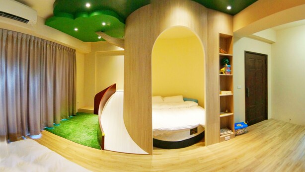 A room with a bed, a curved wooden structure, a green carpet, and a wardrobe. - Bam House B&B (Tainan)