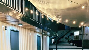 A modern interior with a staircase, a seating area with a table, and a number '02' sign. - Pig Dive Hostel (Moalboal)
