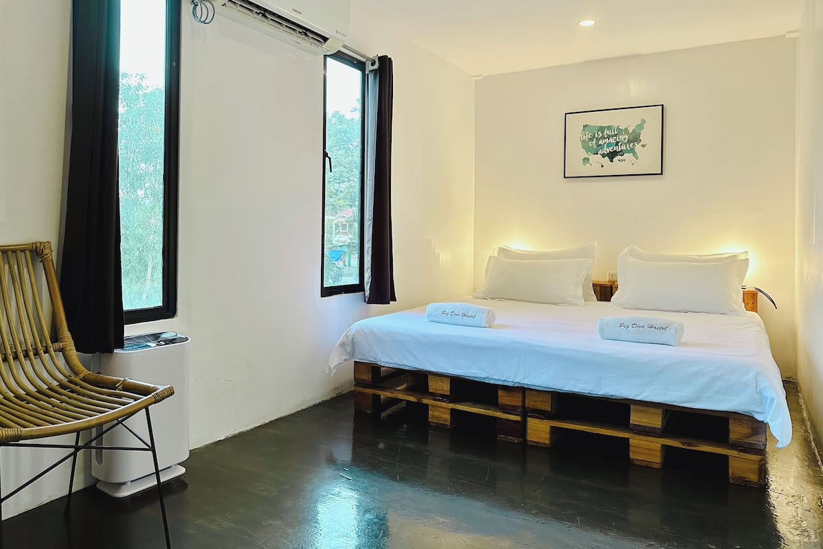 A room with a bed, a chair, and a window.