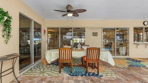 An outdoor patio with a table and chairs, a ceiling fan, and a patterned floor. - Private All Inclusive Vacation Home Near Yacht Club and Ft Myers Beaches (Cape Coral)