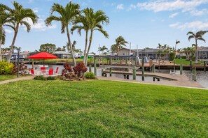 A waterfront property with a dock, a red umbrella, and palm trees.