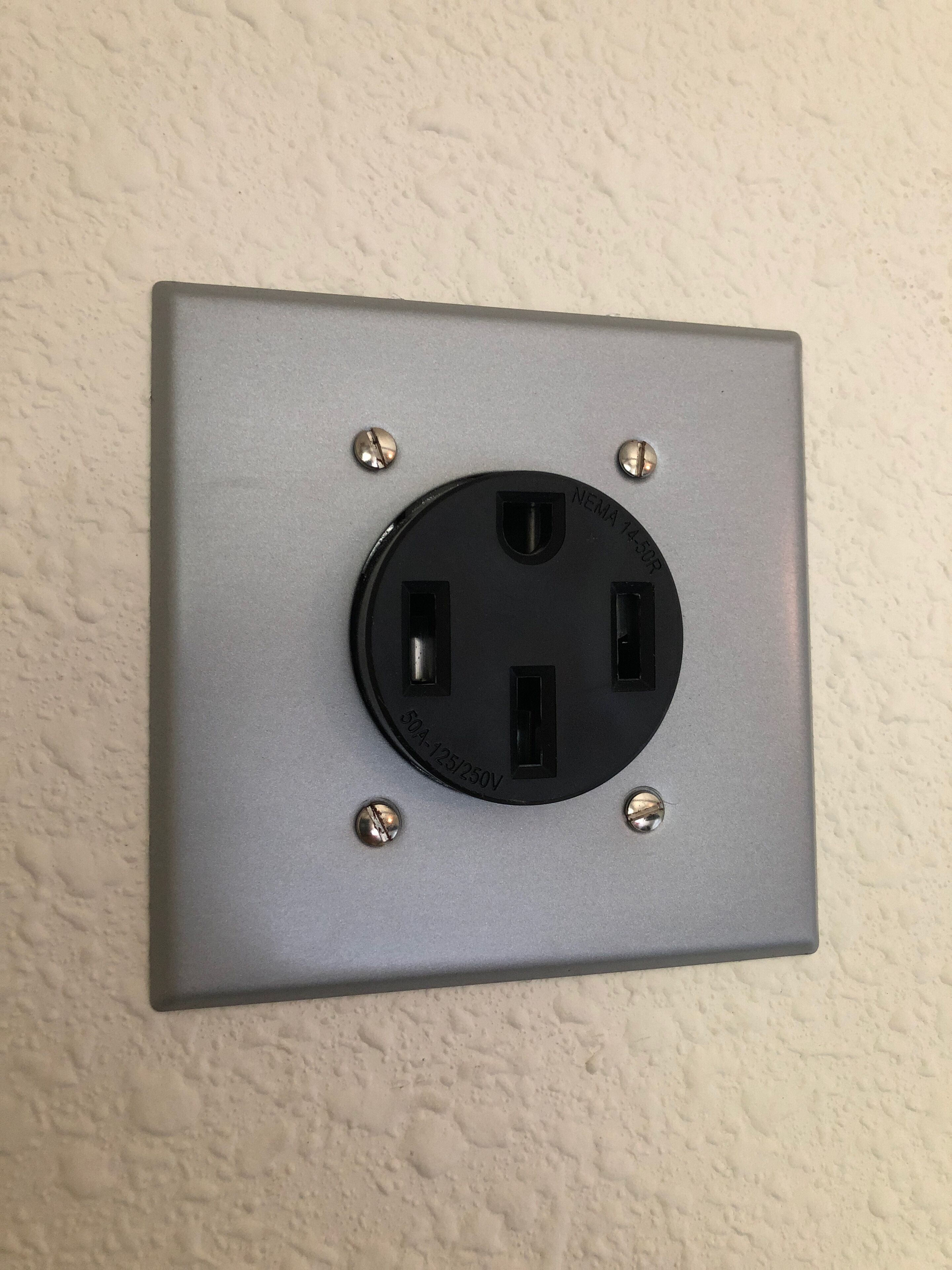 Tomada elétrica padrão com dois interruptores e um parafuso de aterramento, fixada em uma parede texturizada.