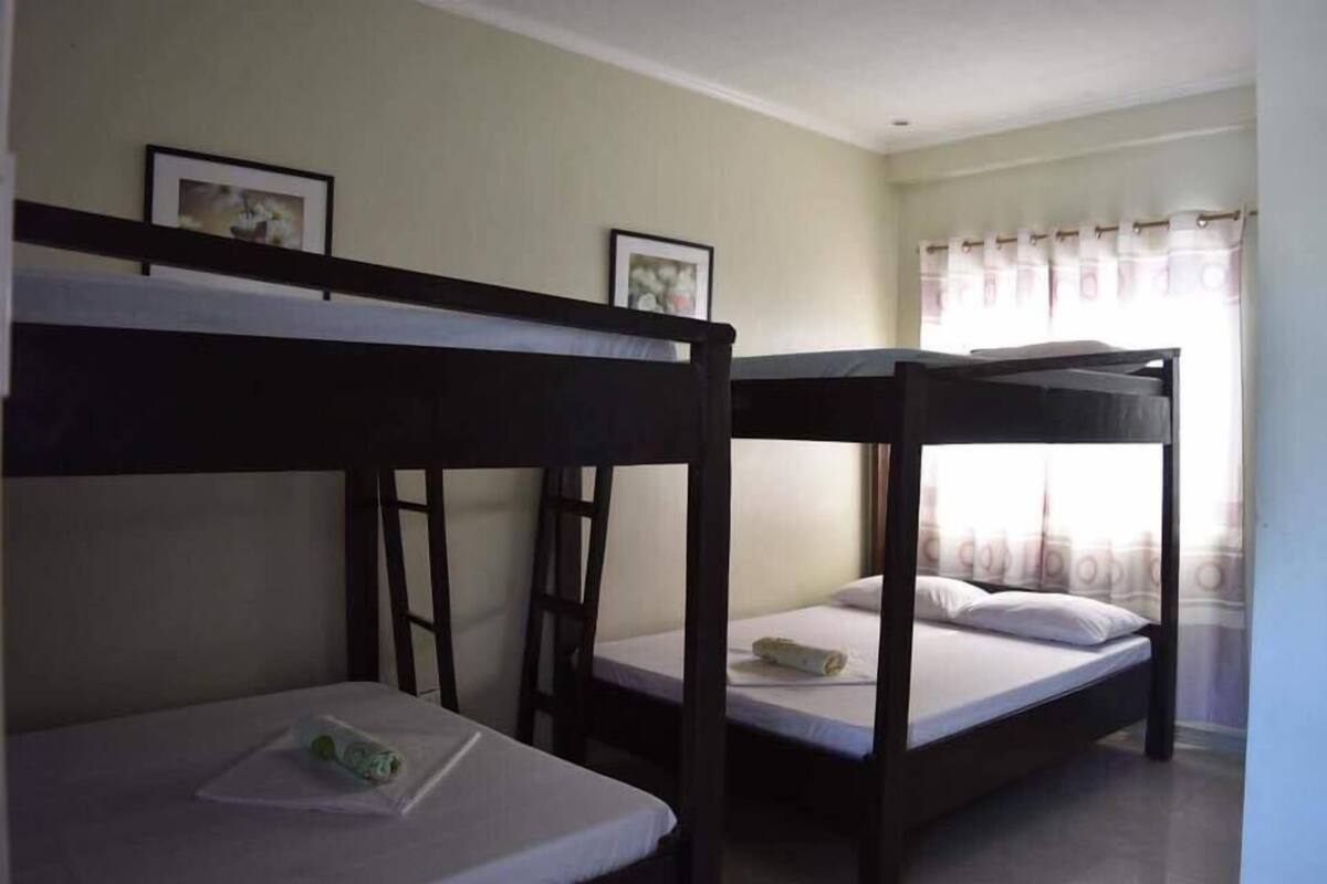 Une chambre avec des lits superposés, une échelle et deux tableaux encadrés accrochés au mur.