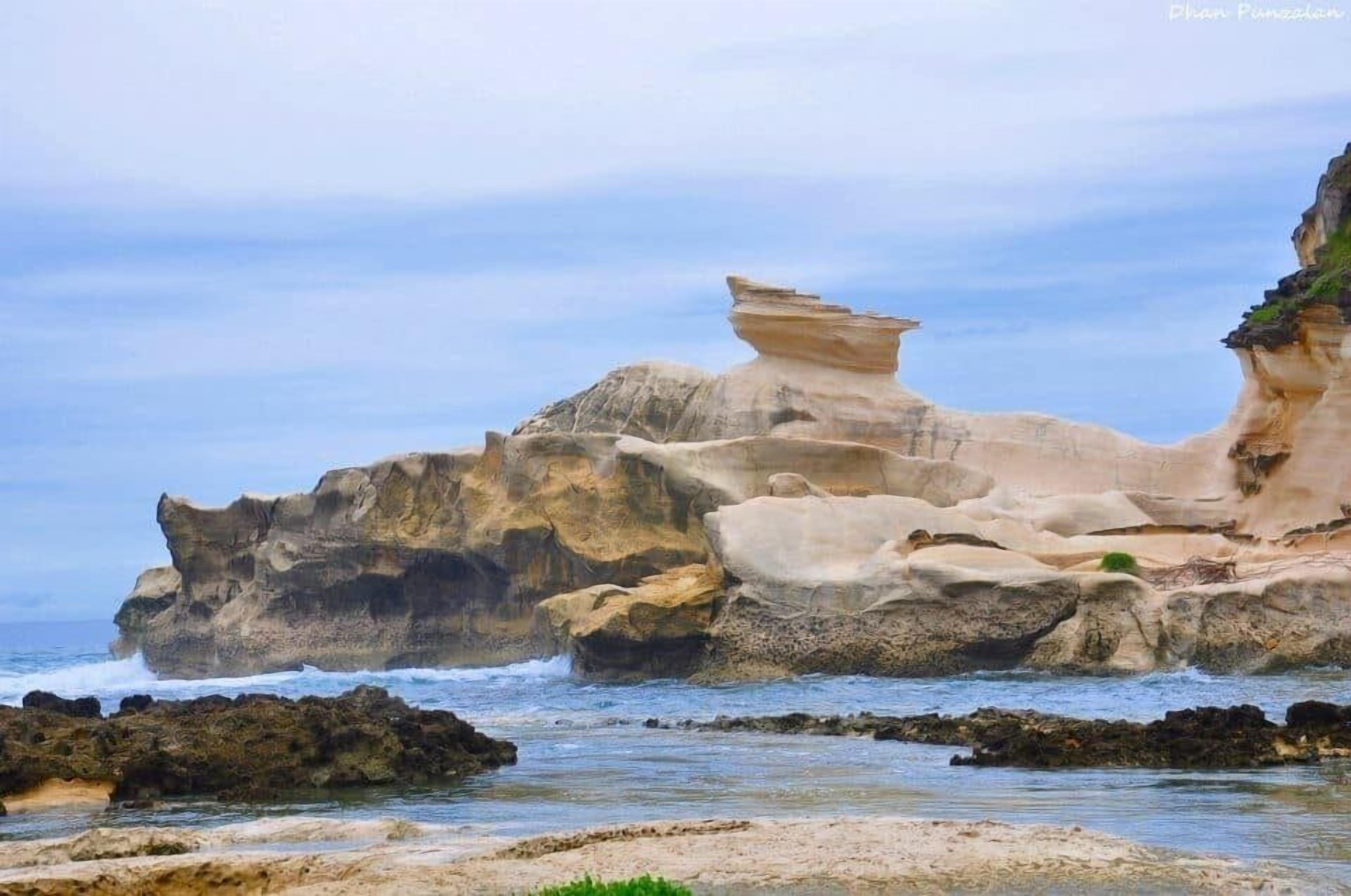 A coastal rock formation with a balanced rock structure.