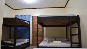 Een kamer met twee stapelbedden, een houten trapje en een gordijn.