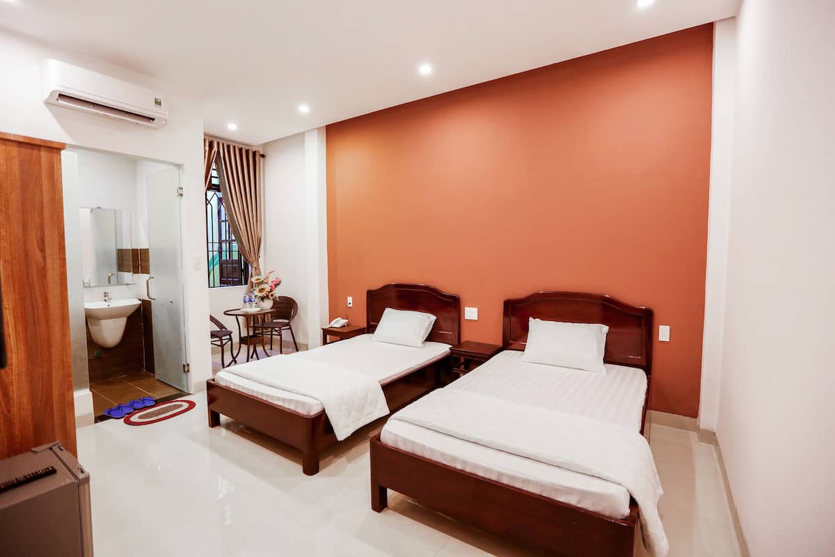 A hotel room with two beds, a bathroom, and a dining area.