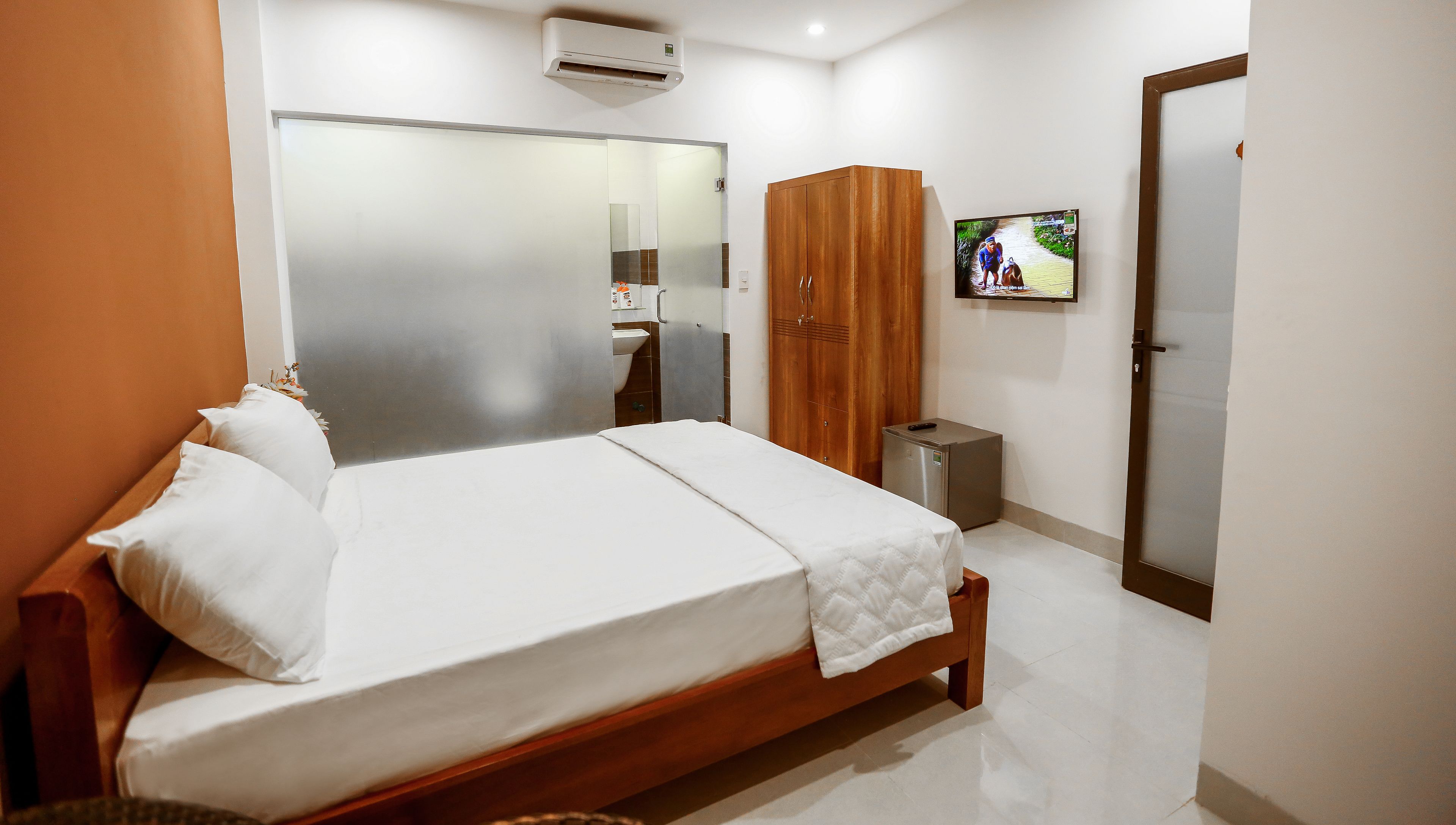 A hotel room with a bed, wardrobe, and a television on the wall.