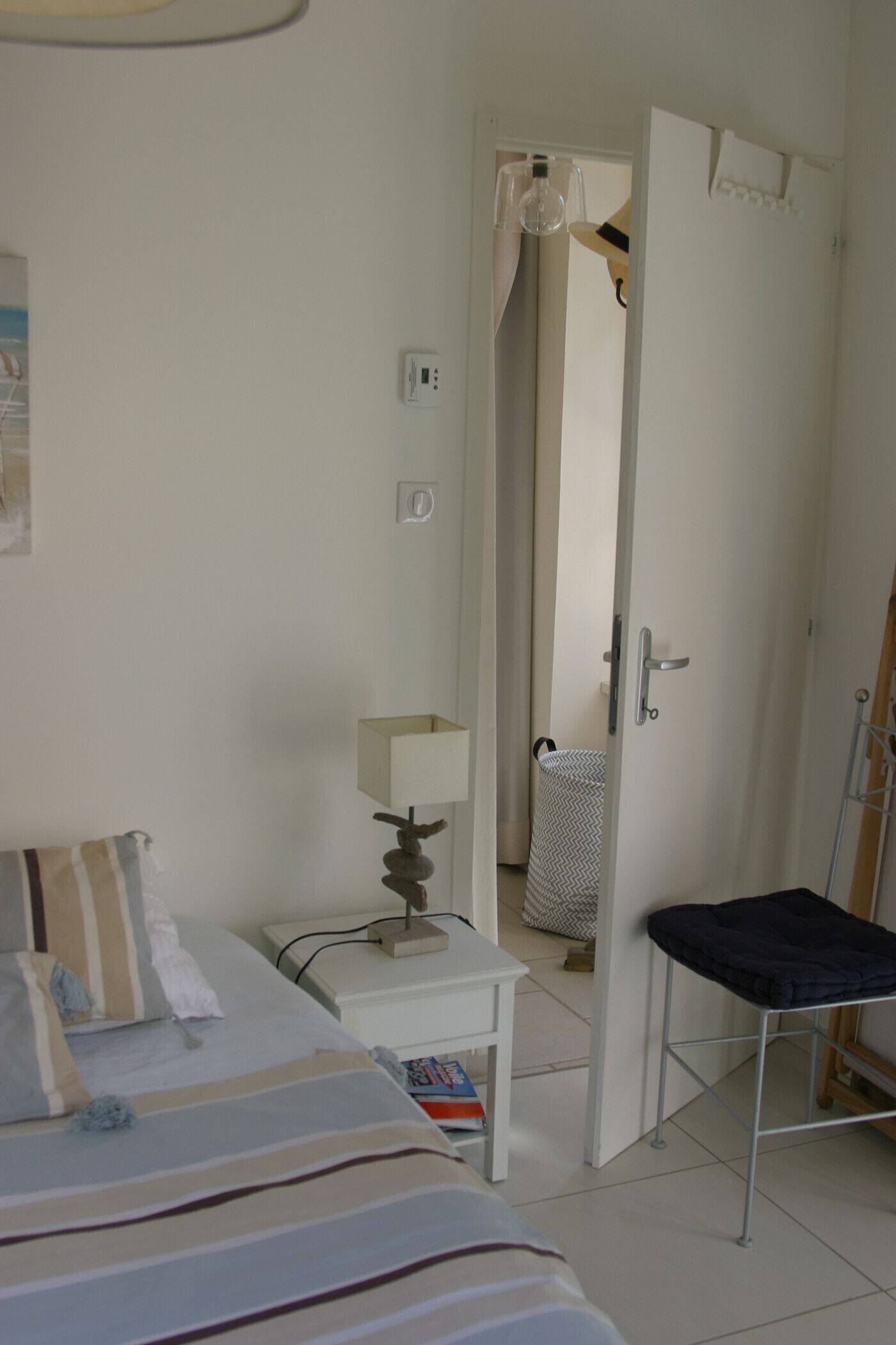 Une chambre à coucher comprenant un lit, une table de chevet, une lampe et une porte donnant sur une autre pièce.