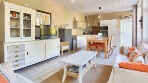 Una sala de estar moderna con un sofá blanco, una mesa de comedor y una cocina al fondo.