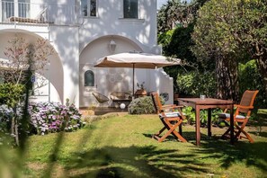 Une terrasse avec une table et des chaises, un fauteuil suspendu et une lampe.