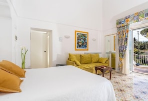 Una habitación de hotel con una cama grande, un sofá, una mesita y un cuadro en la pared.