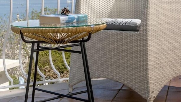 A balcony with a wicker chair, a glass table, and a view of the sea. - Il Sogno (Anacapri)