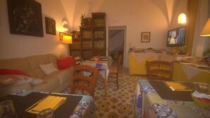 A cozy living room with a sofa, dining table, chairs, and a bookshelf. - Il Sogno (Anacapri)