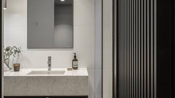 Un baño moderno con un espejo grande, un lavabo y una repisa con toallas enrolladas.