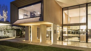 A modern hotel with a glass facade, outdoor seating area, and a visible elevator. - Mercure Sydney Rouse Hill (Rouse Hill)