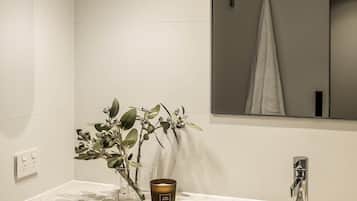 Un baño con pared de azulejos blancos, un espejo, un lavabo, un grifo y una vela.