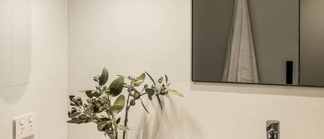 A bathroom with a white tiled wall, a mirror, a sink, a faucet, and a candle.