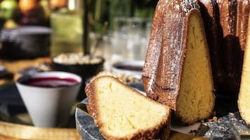 Una torta bundt su un piatto con un coltello, una ciotola di marmellata e un bicchiere di bevanda sullo sfondo.