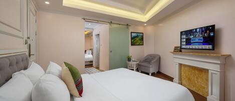 Una habitación de hotel con una cama grande, televisión, chimenea y una puerta que da a otra habitación.