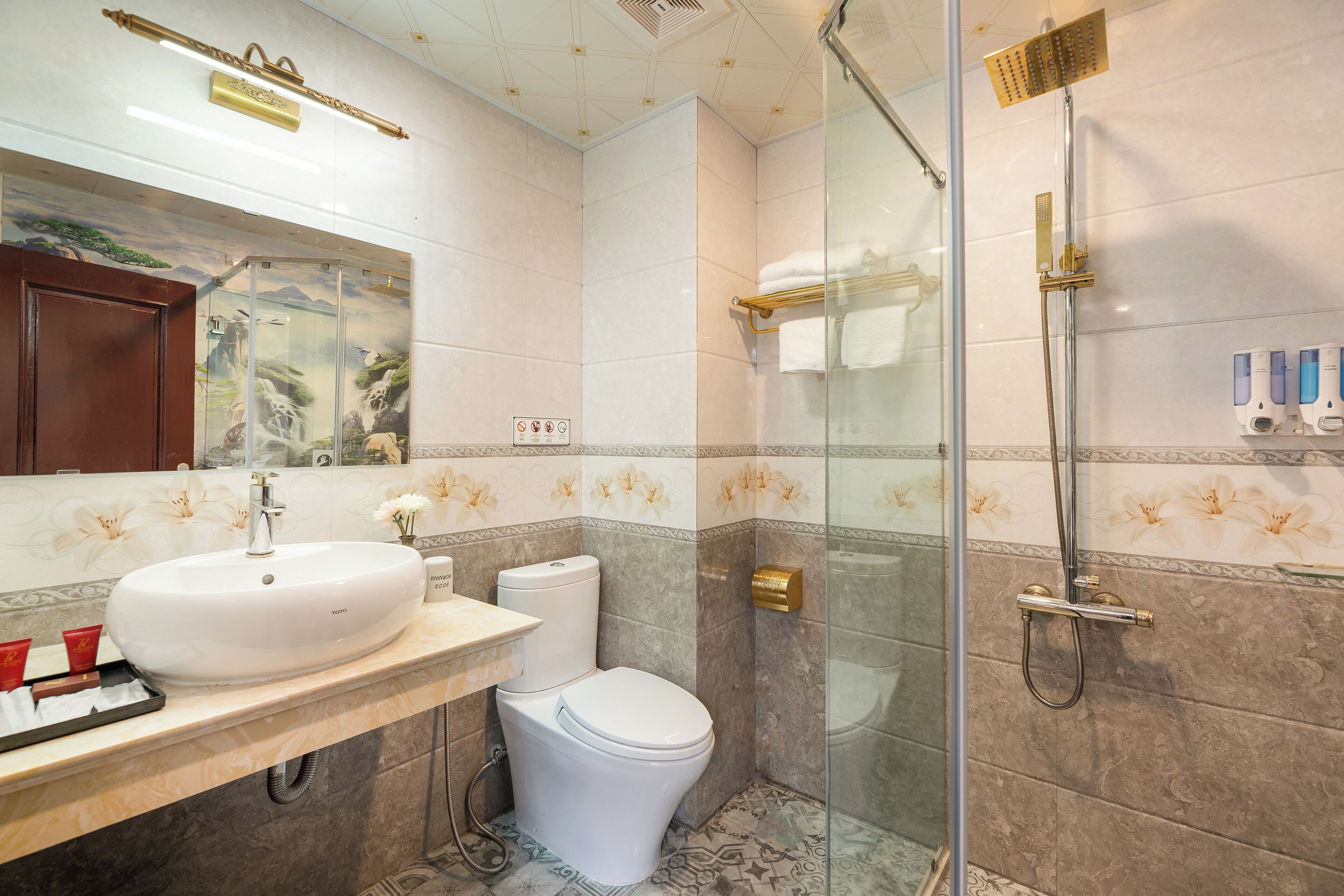 Un baño con un lavamanos grande y blanco, un inodoro y una zona de ducha con paredes de vidrio.