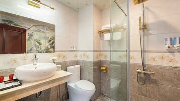 Un baño con un lavamanos grande y blanco, un inodoro y una zona de ducha con paredes de vidrio.