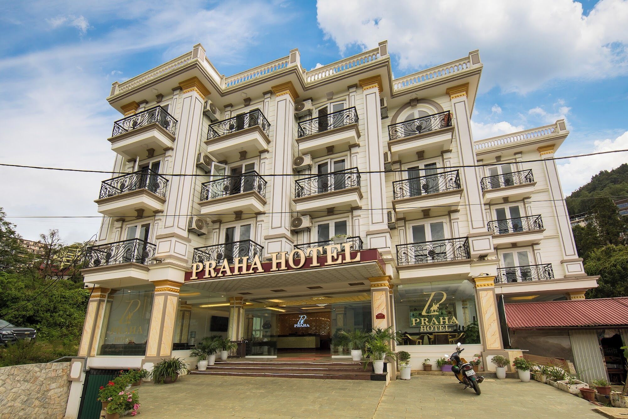 Een meerhoog hotel met een statig entree, balkons en een bord waarop 'Praha Hotel' staat.