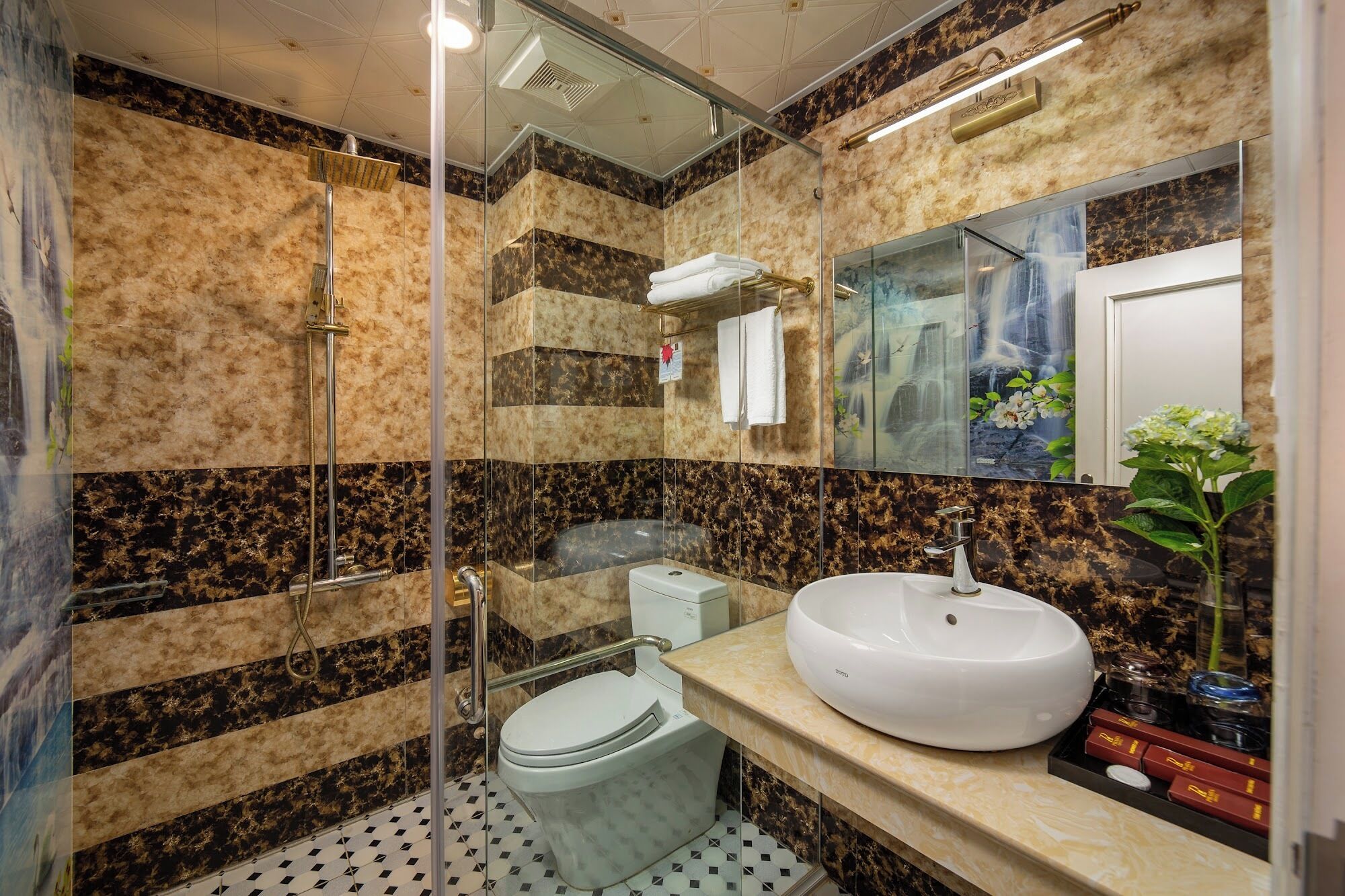 Une salle de bain avec une douche à parois de verre, des toilettes, un lavabo avec un miroir et une plante décorative.