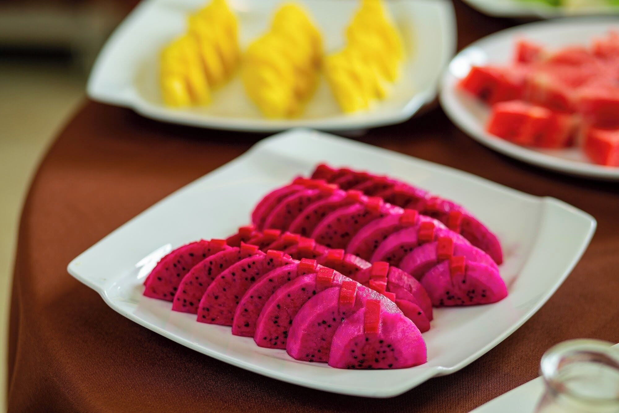 Une assiette de tranches de fruit du dragon est posée sur une table.