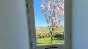 Eine Tür mit Blick auf einen Baum mit rosa Blüten und ein grasbewachsenes Feld.