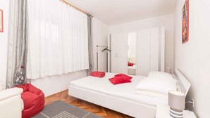 Ein modernes Schlafzimmer mit einem Bett, einem roten Sitzsack, einer Nachttischlampe und einem Kleiderschrank.