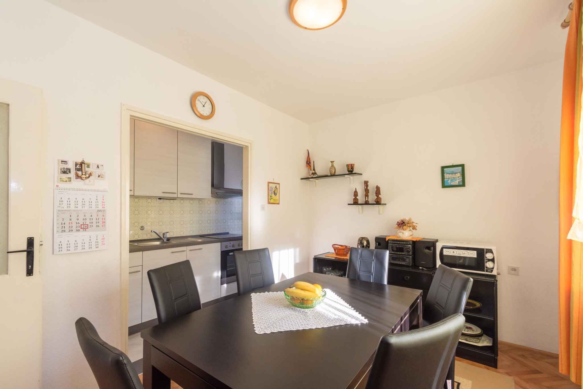 A compact kitchen with a dining table, chairs, and a clock on the wall.