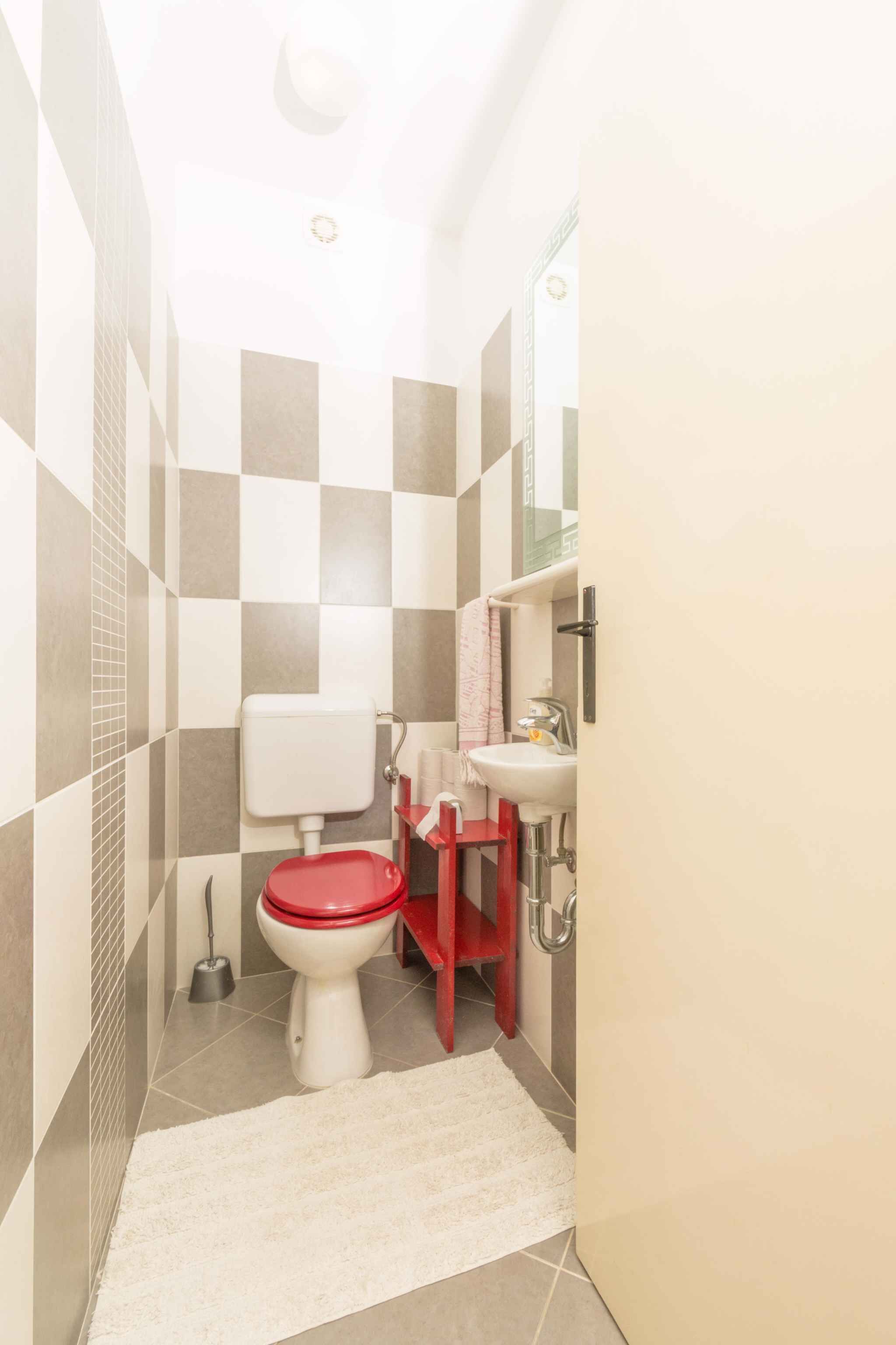 Une petite salle de bain comprenant des toilettes, un lavabo et un meuble rouge.