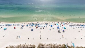Una playa con numerosas sombrillas y tumbonas, y una vista despejada del océano, además de una orilla arenosa.